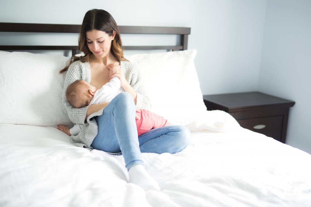 Mom Breastfeeding Baby Sitting Up In Bed for Breastfeeding School www.breastfeedingschool.com by Haydee Montemayor